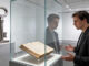 Mann mit altem Buch und großem Schlüssel im Museum
