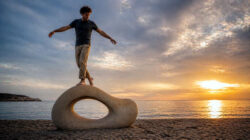 Spiritueller Narzissmus Balance an Strandskulptur bei Sonnenuntergang