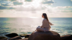 Wirkung von Meditation eine Frau sitzt auf einem Felsen am Meer