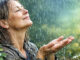 Frau lächelnd im Regen und hält die Hände hoch